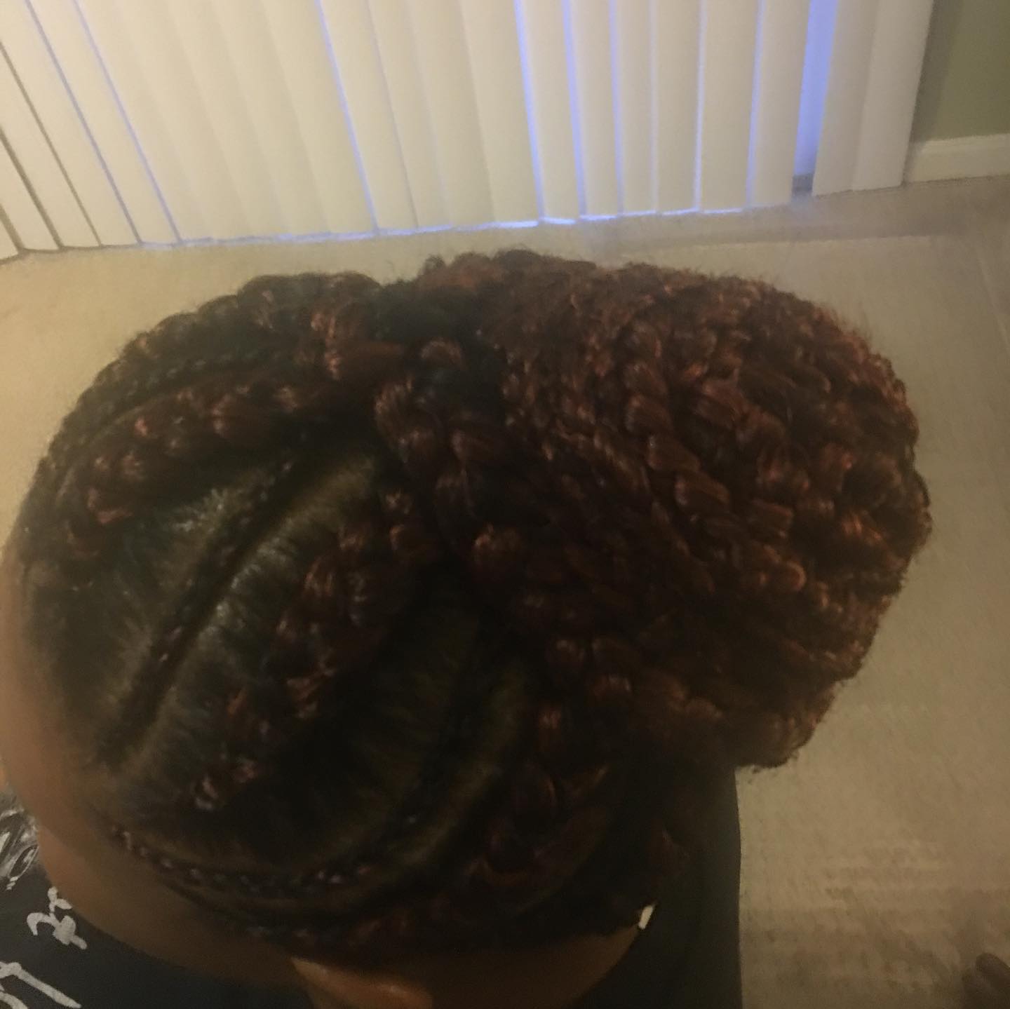 Overhead view of a reddish-brown braided bun hairstyle on a person's head, seen from above