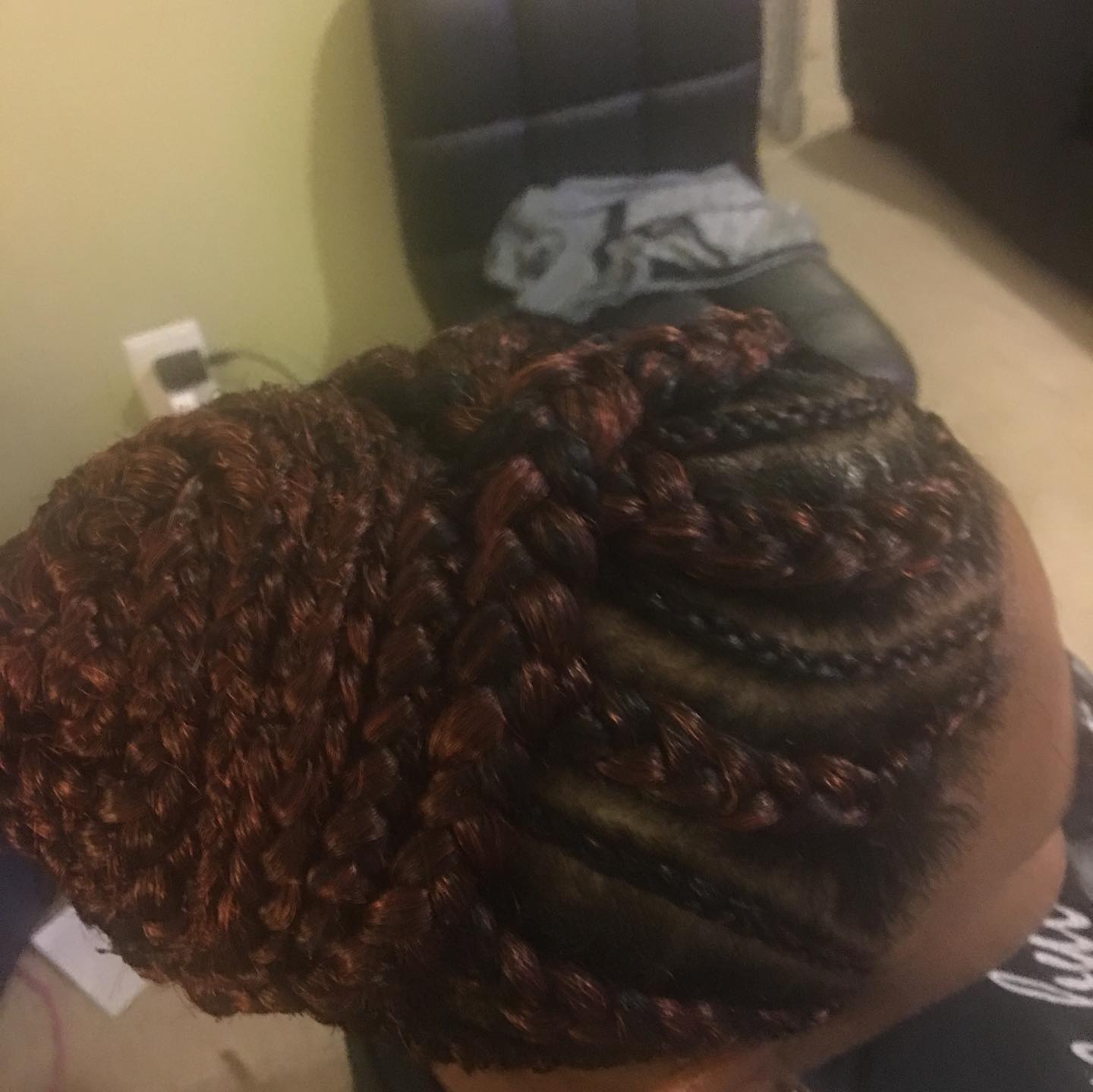 Overhead close-up view of an intricately woven reddish-brown braided bun hairstyle