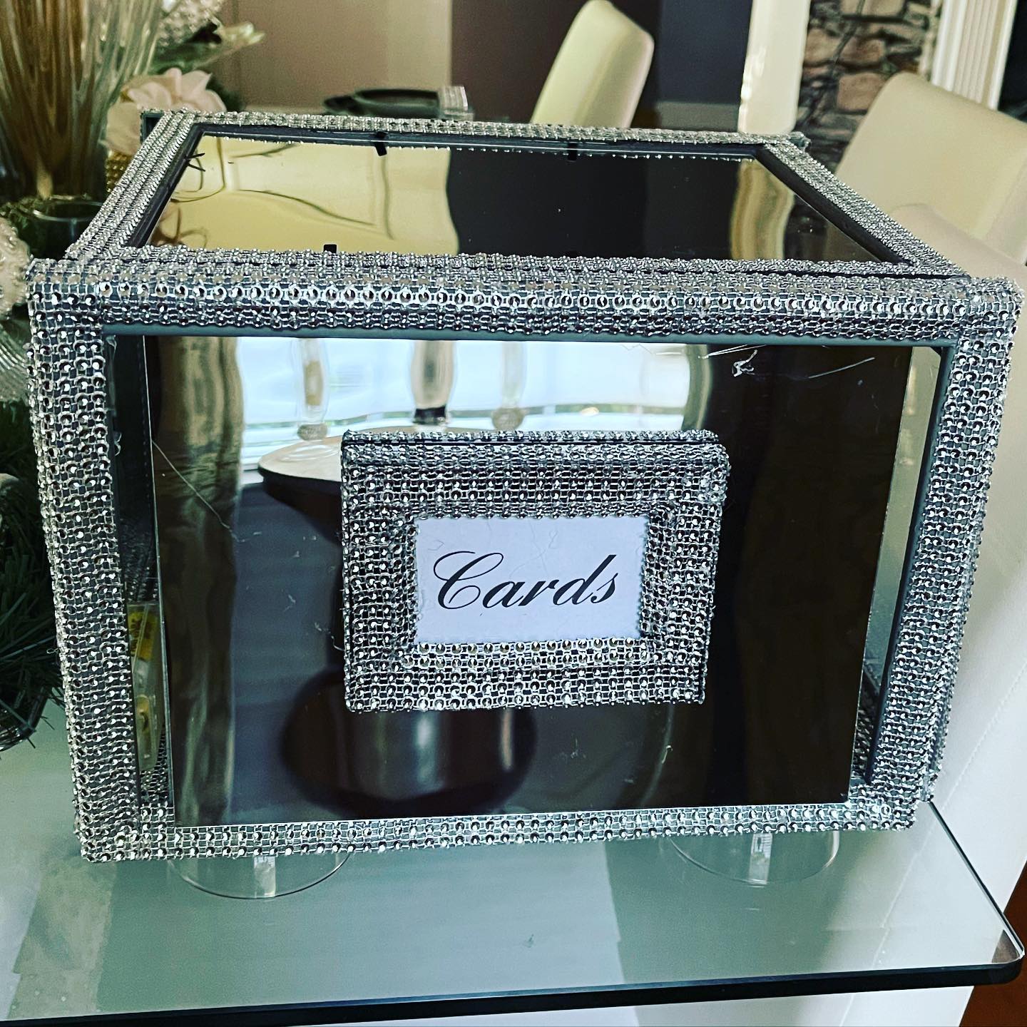 Mirrored card box trimmed in rhinestones with a 'Cards' label on a glass table