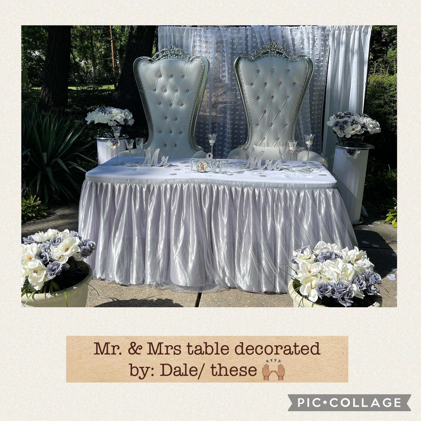 Two tufted high-back chairs in ivory sit behind a table with a silver skirt, flanked by floral arrangements and a sheer draped backdrop outdoors.